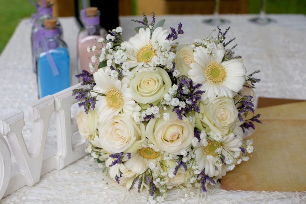 Bouquet de novia con margaritas, rosas blancas y flores lilas.