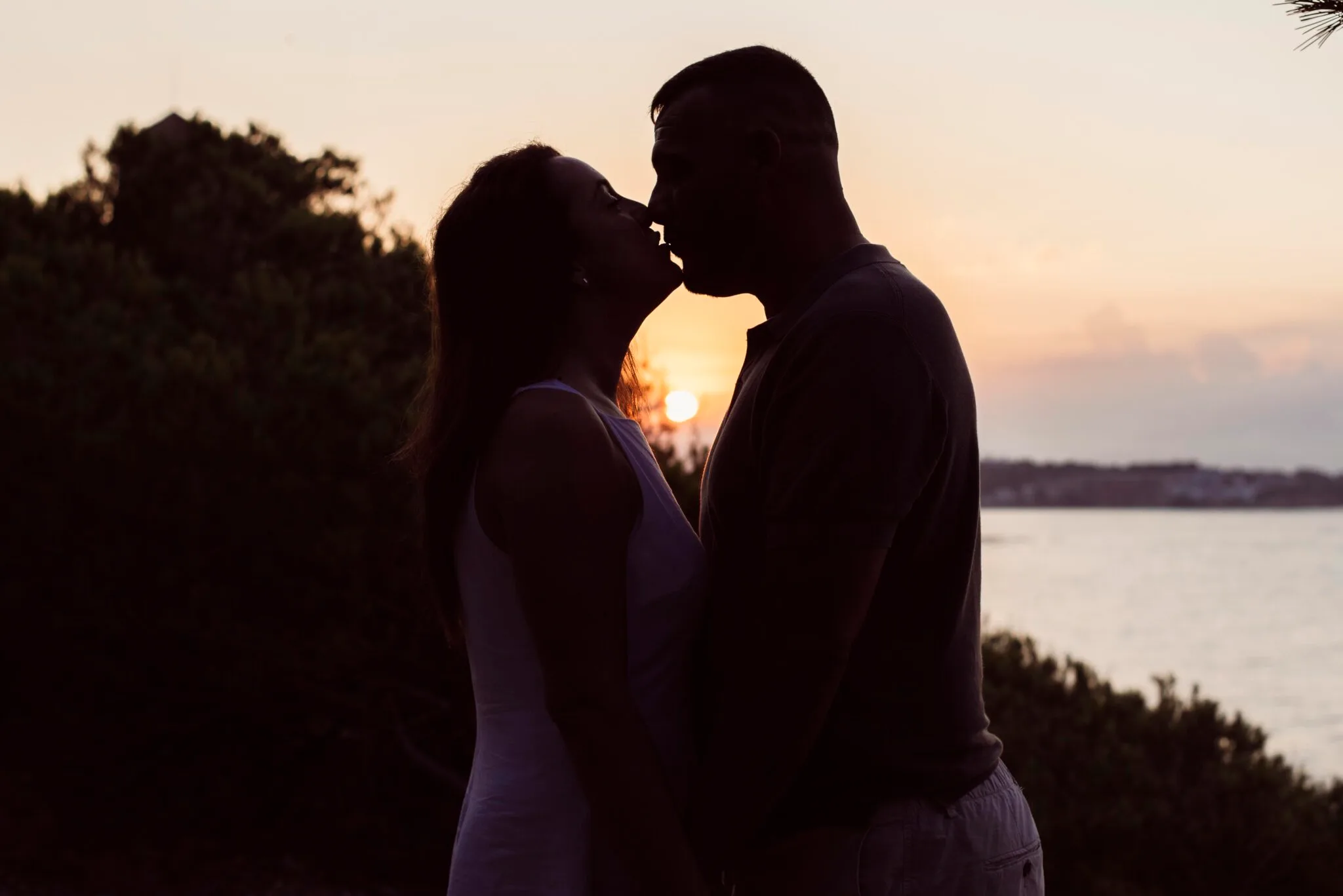 Pareja abrazándose al atardecer frente al mar, fotografiada por Marbellot Fotografía