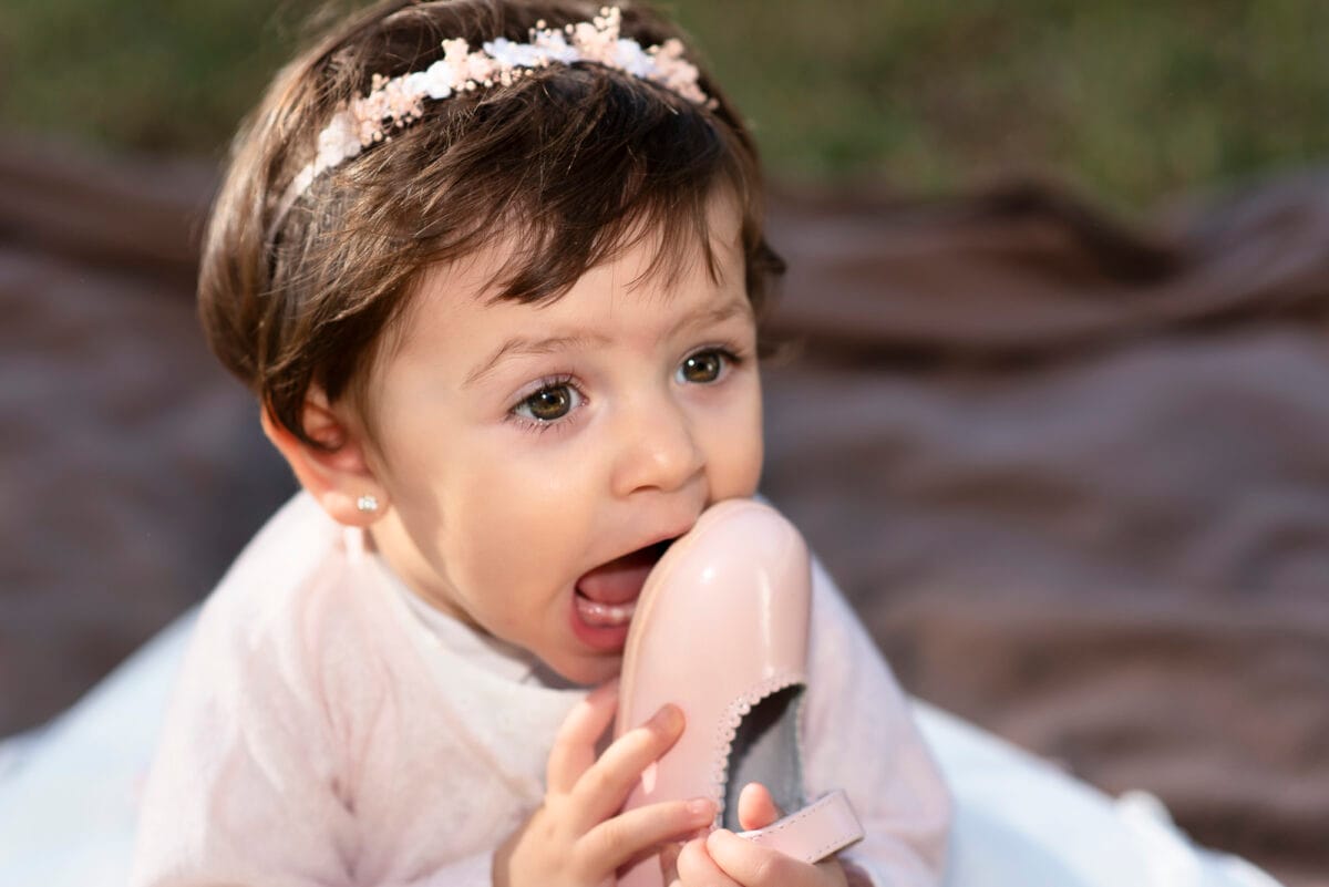 Niña pequeña mordiendo su zapato en el Parque de los Pescadores de Cambrils - Fotografía natural infantil Marbellot