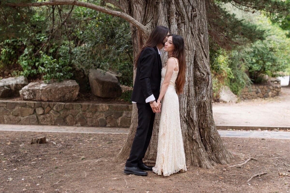 Beso en la mejilla junto al tronco de un árbol, preboda en Poblet