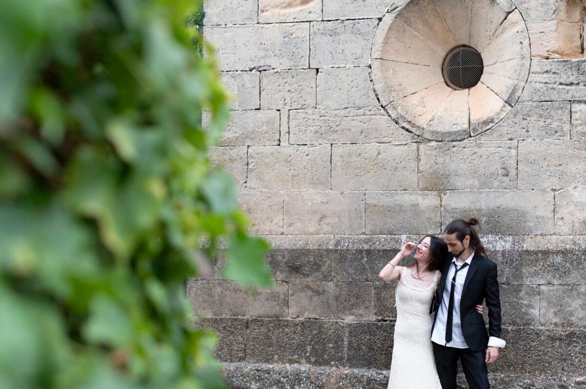 Pareja riendo bajo un rosetón de piedra entre viñas en Poblet