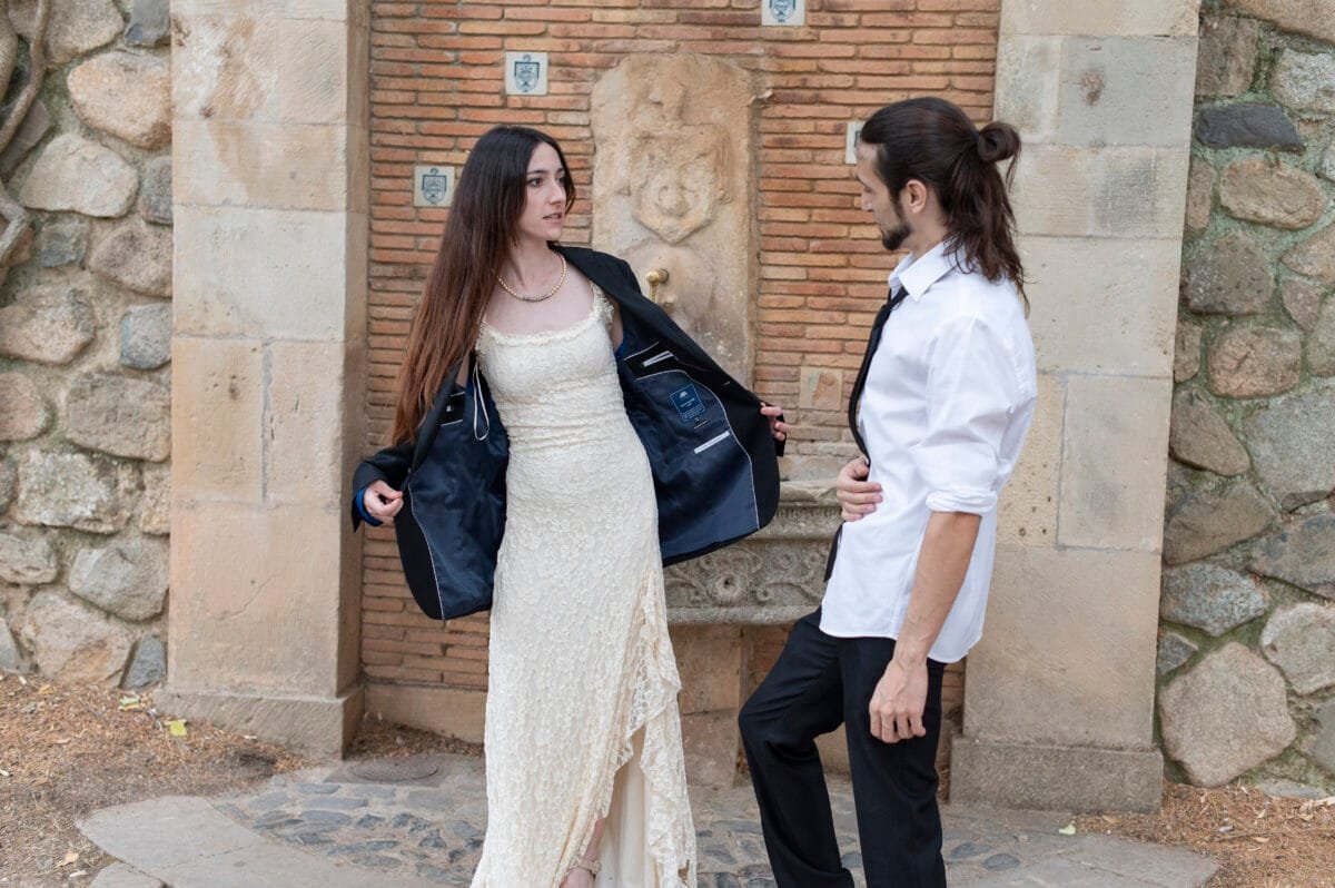 Novia con la chaqueta del novio junto a una fuente de Poblet